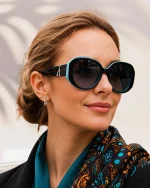Woman wearing black and turquoise polarized sunglasses with oversized round frames and dark tinted lenses