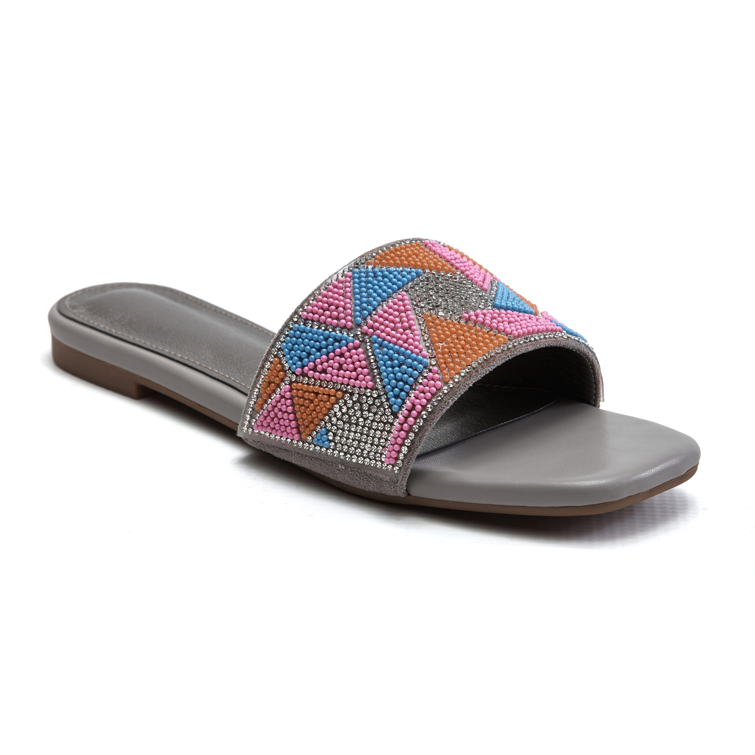 Close-up of beaded embellishments on sunset pink slip-on sandals Close-up of beaded embellishments on sunset pink slip-on sandals