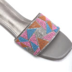 Close-up of beaded embellishments on sunset pink slip-on sandals