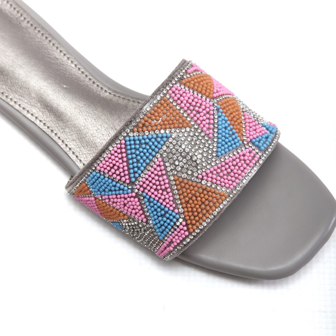 Close-up of beaded embellishments on sunset pink slip-on sandals
