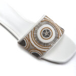 Close-up of ivory, gold, silver, and grey beadwork on white sandal strap