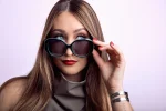 Woman wearing black and turquoise polarized sunglasses with oversized round frames and dark tinted lenses