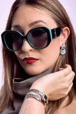 Woman wearing black and turquoise polarized sunglasses with oversized round frames and dark tinted lenses